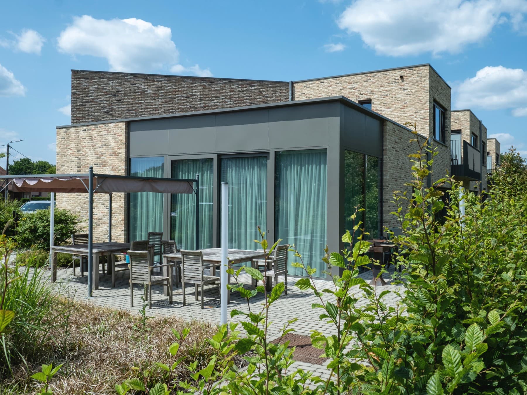 Maison de Huis50 avec terrasse couverte et arbres en arrière-plan.