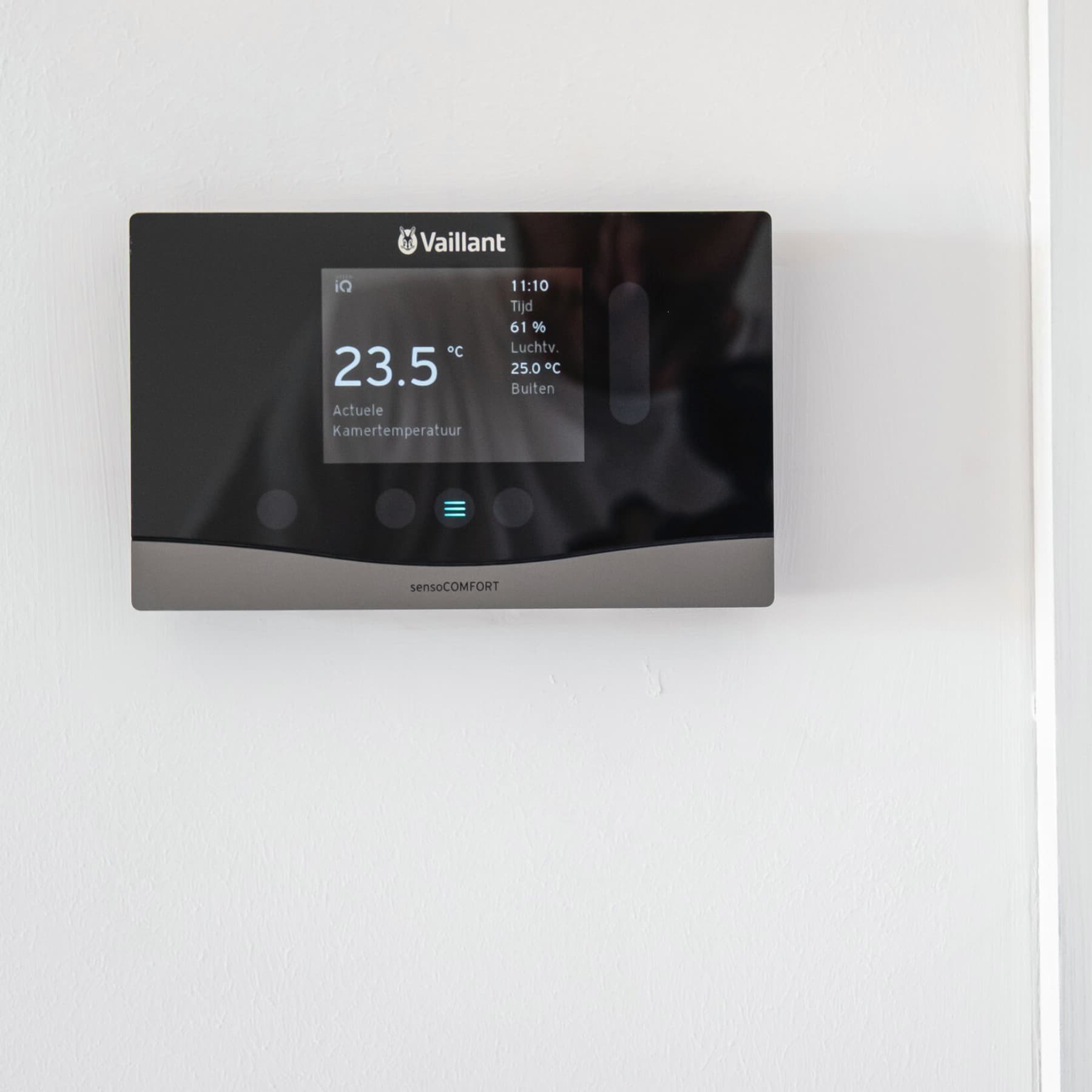 Régulateur sensoCOMFORT en fonction de la température extérieure, fixé sur un mur blanc. La température souhaitée est réglée sur 23,5 °C.