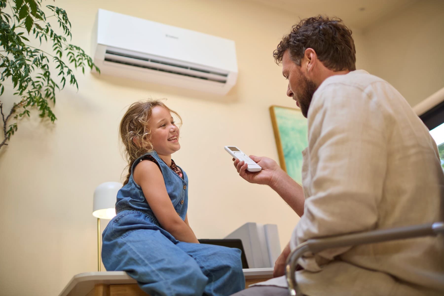 Une fille et son père devant un climatiseur