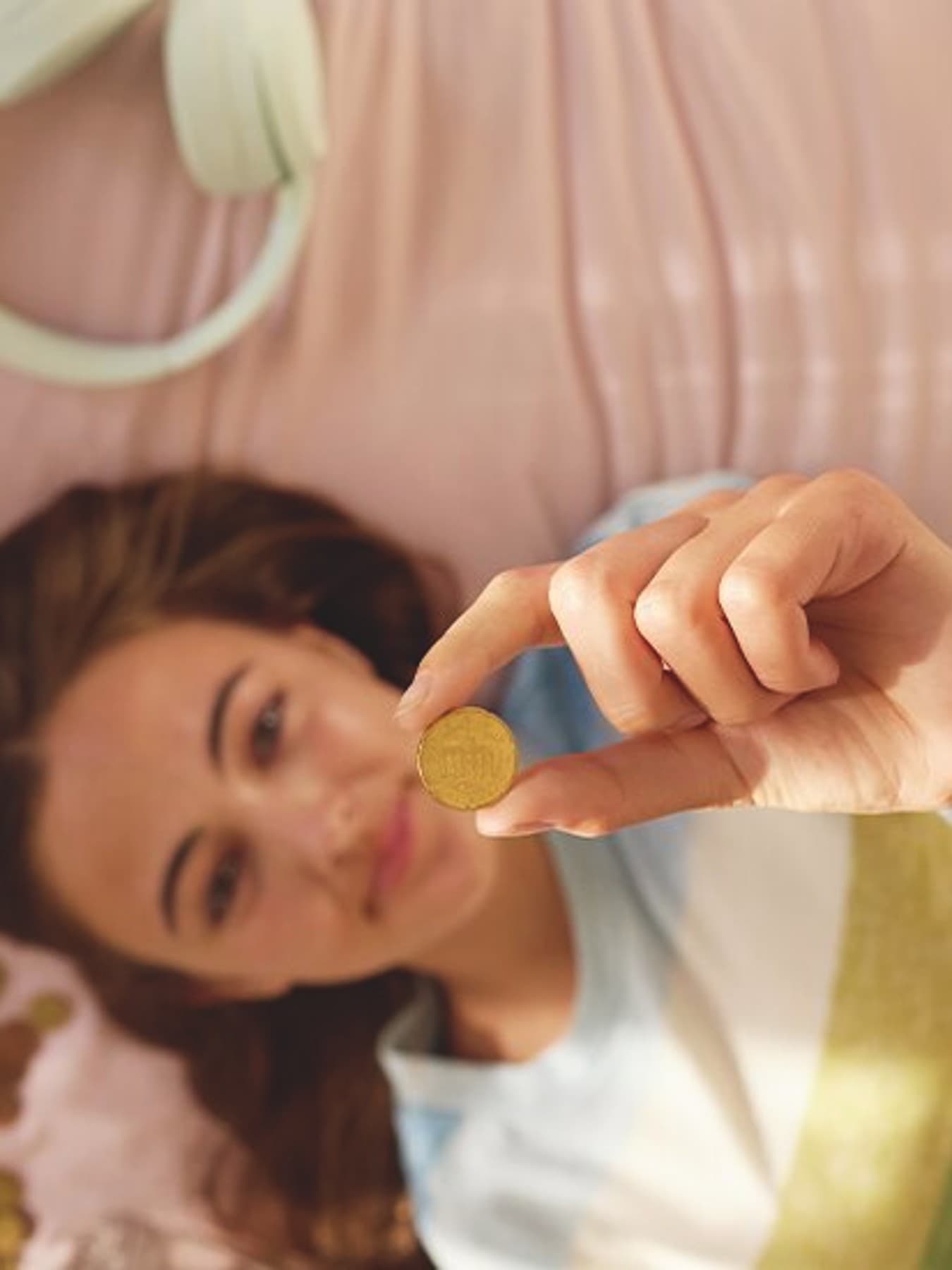 Une femme est allongée sur son lit et montre une pièce de 50 centimes