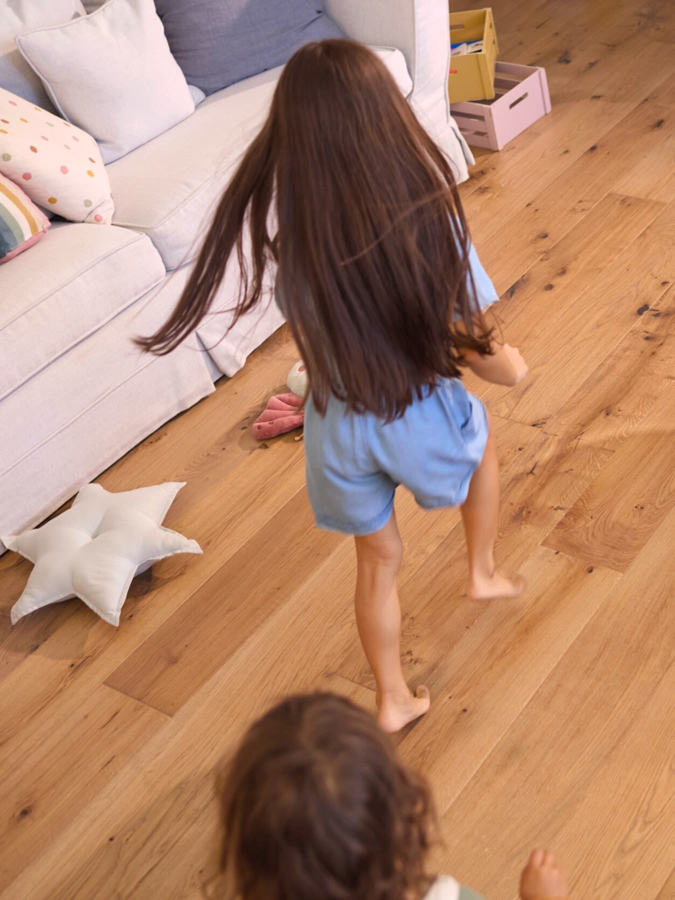 deux enfants courant pieds nus sur le parquet de la maison