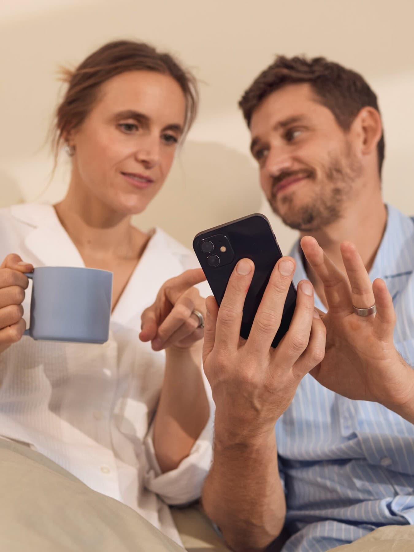 Couple assis dans leur lit en train d'écrire sur leur téléphone