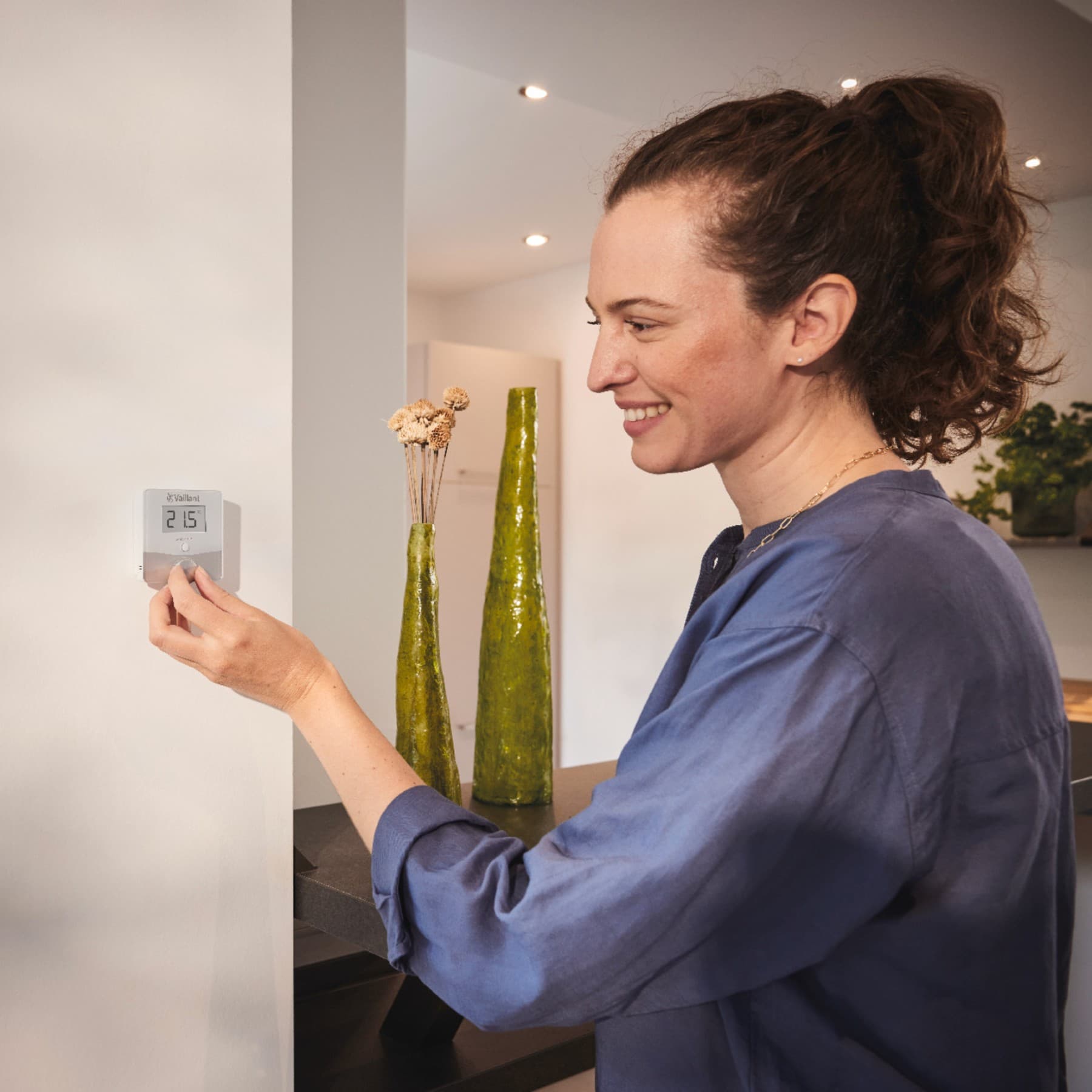Une femme règle la température d'un thermostat