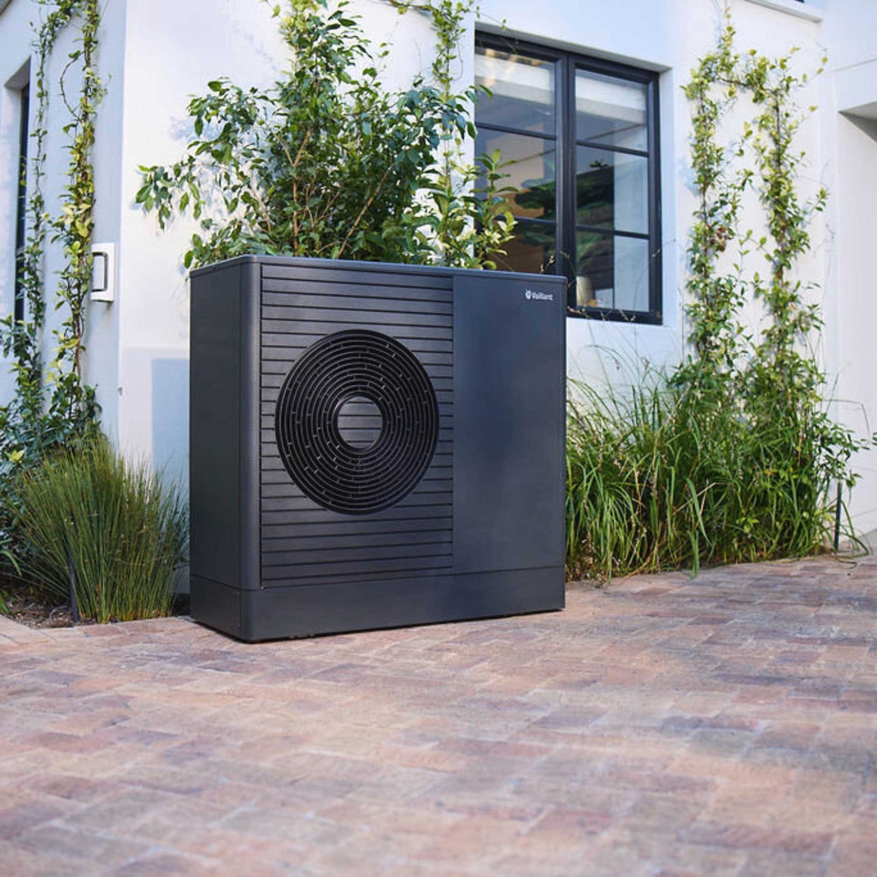 Pompe à chaleur Dark Vaillant aroTHERM plus dans le jardin devant une maison