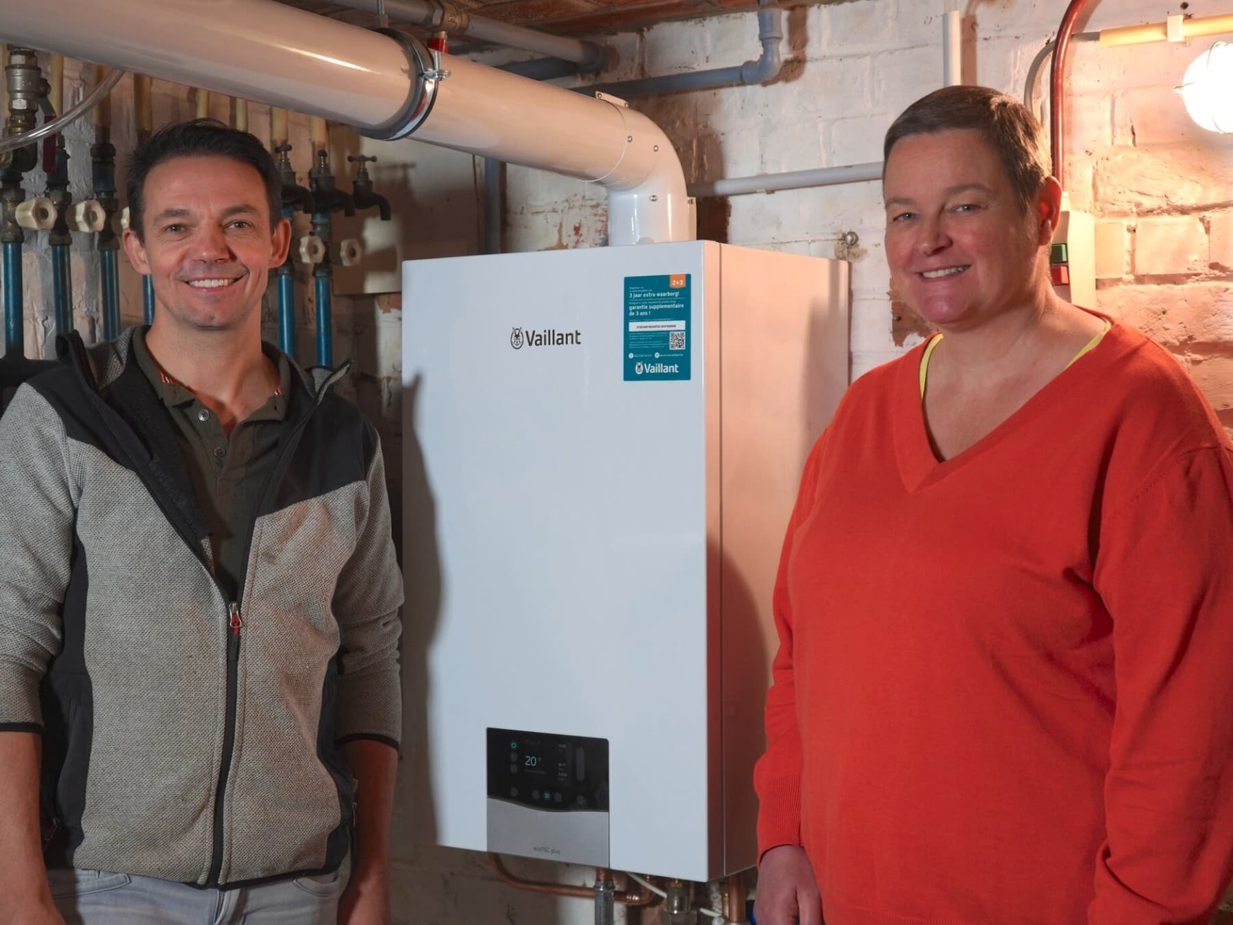Hans, l'installateur, et Anke, la cliente, se trouvent dans une cave, à côté d'une chaudière à condensation ecoTEC