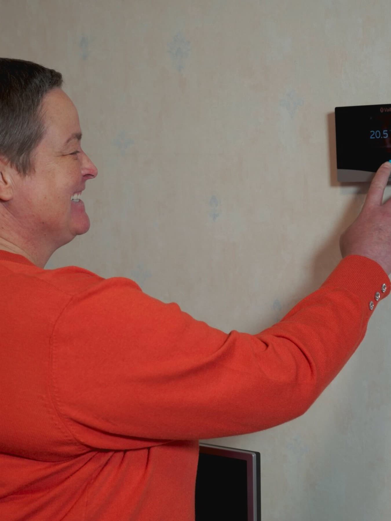 Anke, une cliente, règle les paramètres d'un thermostat mural