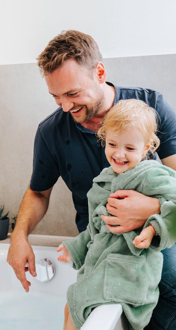 Un père et son enfant assis près de la baignoire.