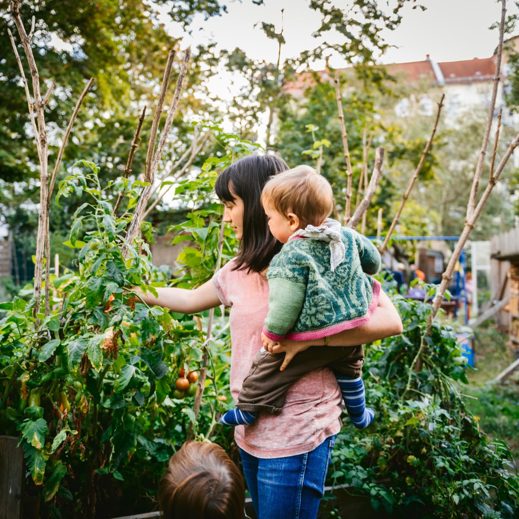 Femme avec un enfant dans les bras dans un potager