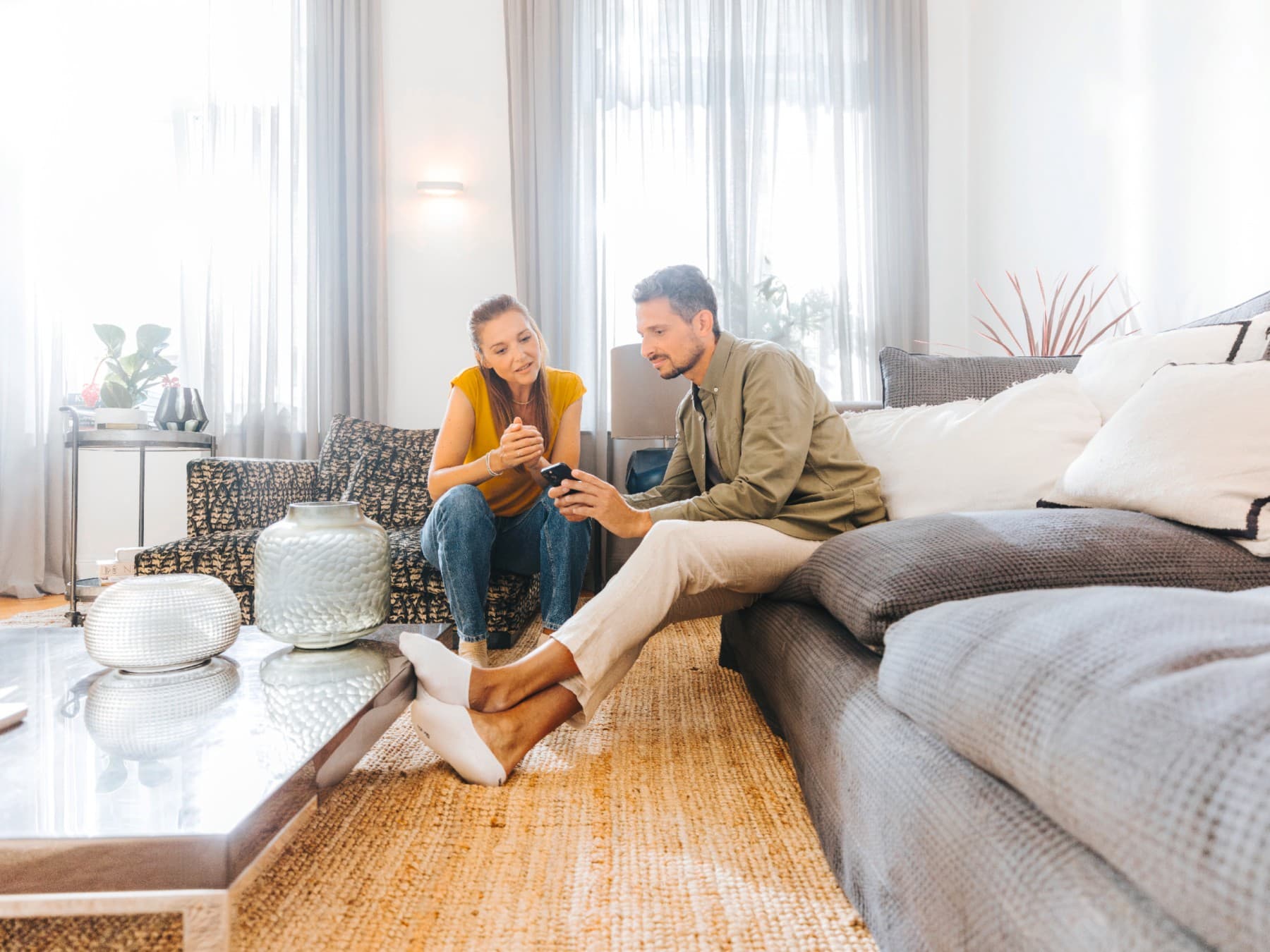 Un couple est assis dans le canapé et regarde un smartphone