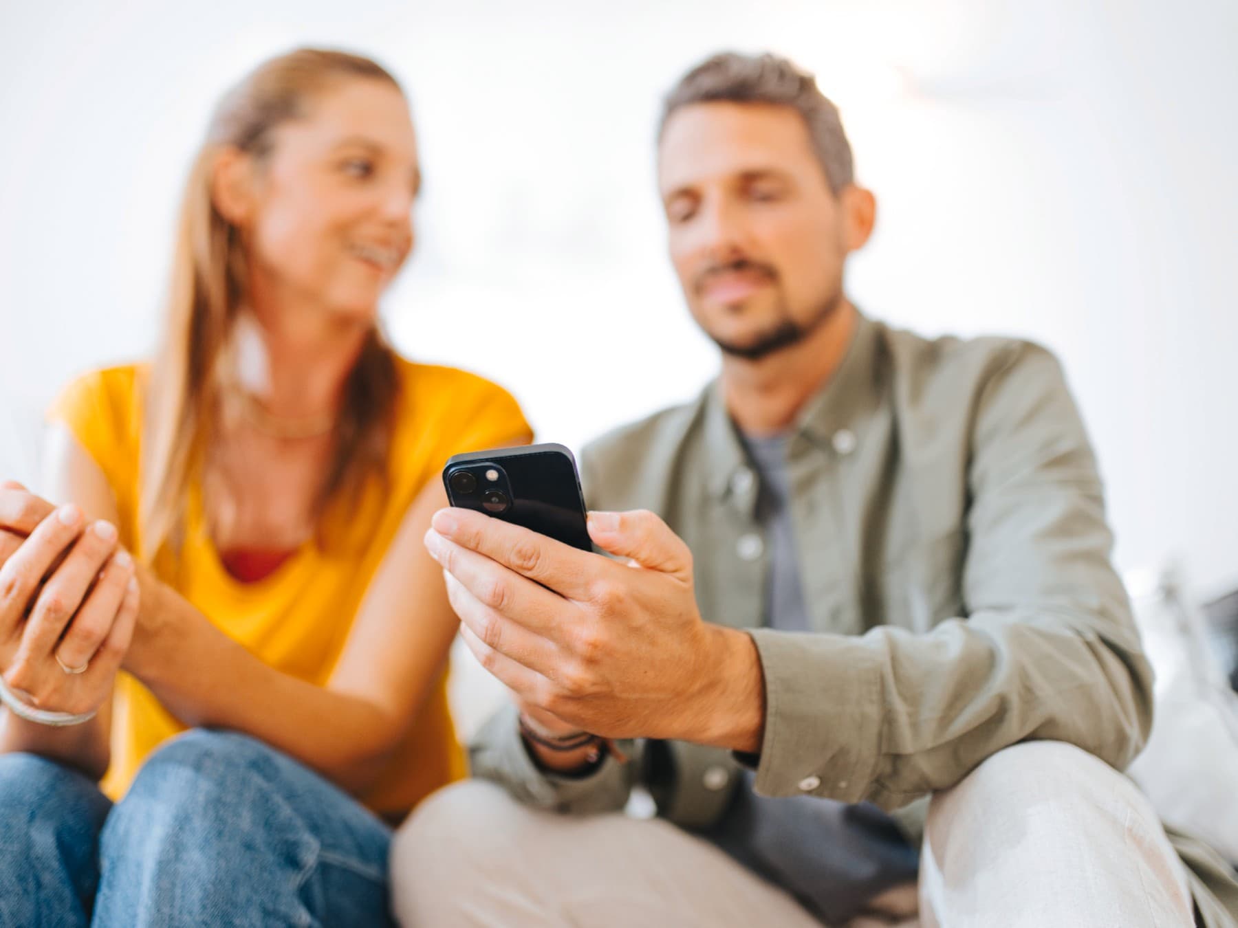 Un couple est assis dans le canapé avec un smartphone