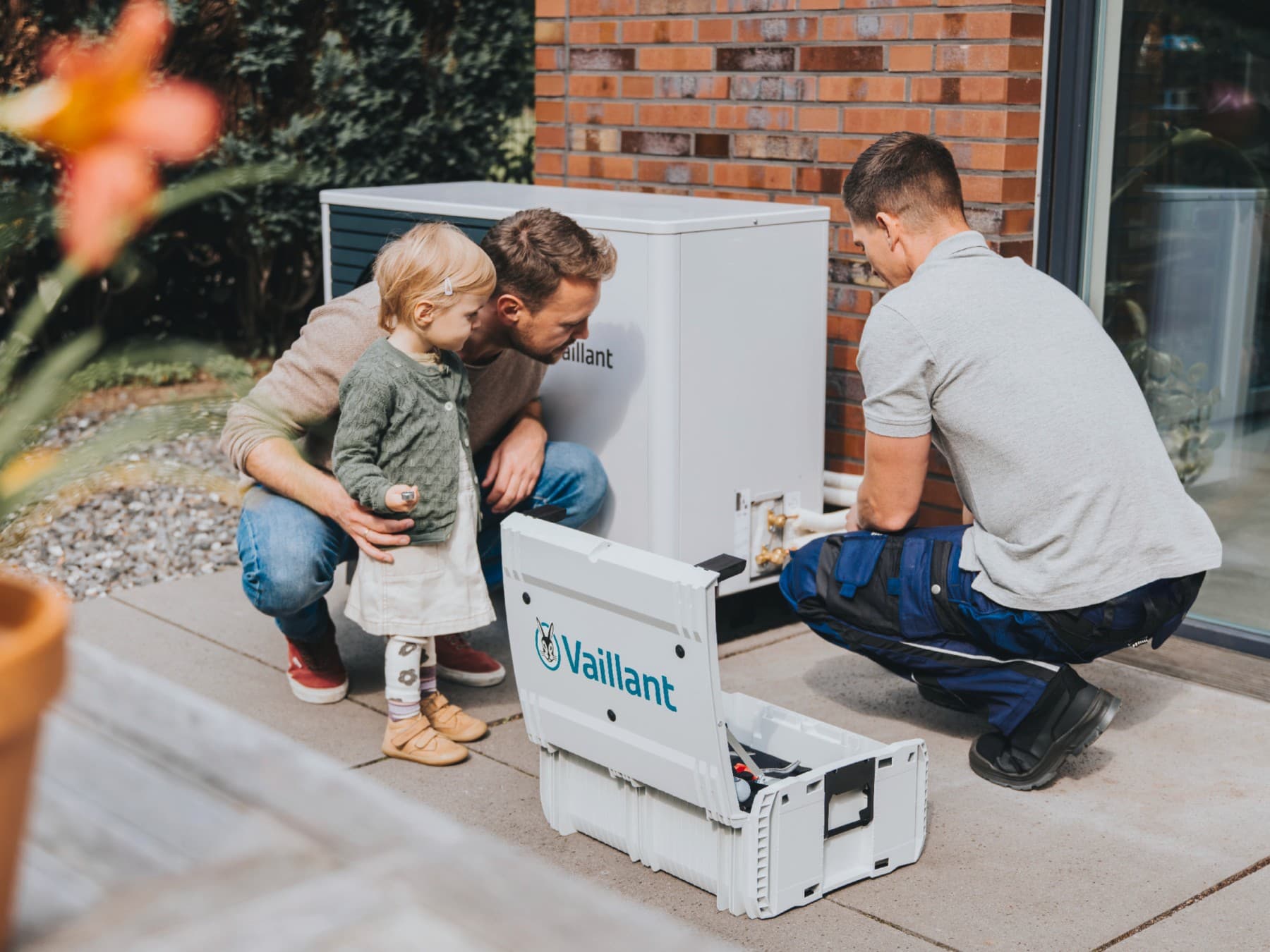 Un père et sa fille regardent un installateur installer une pompe à chaleur.