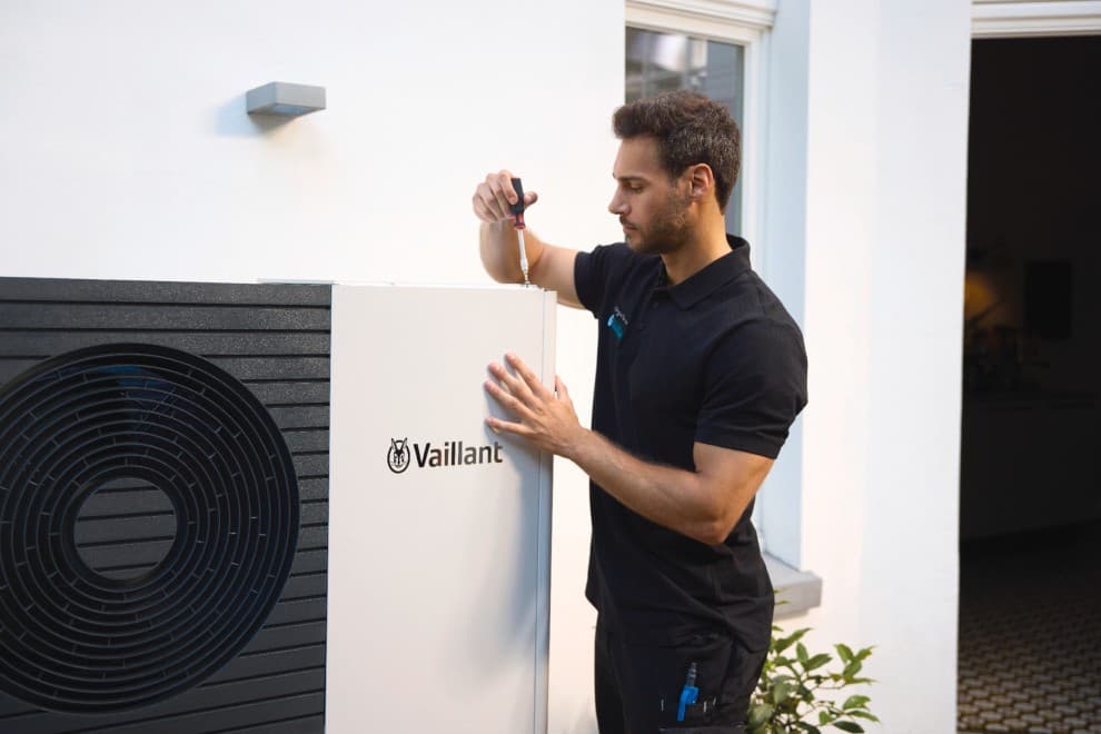Un installateur Vaillant travaille sur une pompe à chaleur.