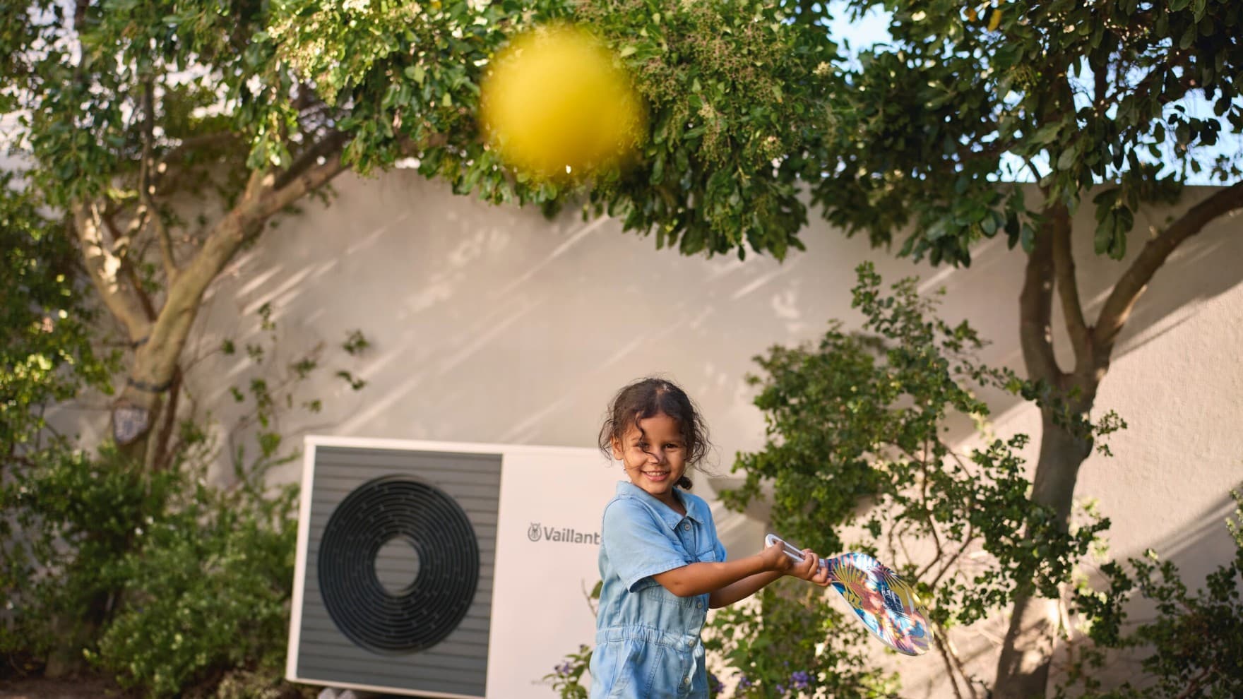 Un enfant joue dans le jardin avec une balle de tennis