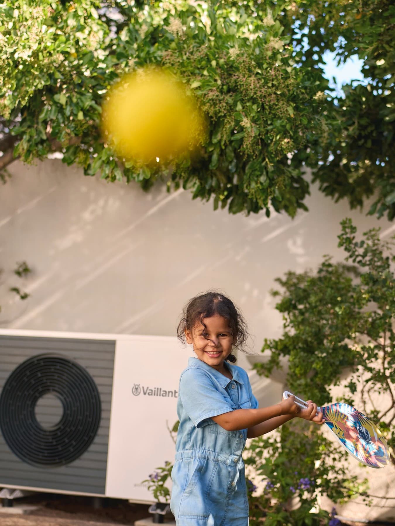 Un enfant joue dans le jardin avec une balle de tennis