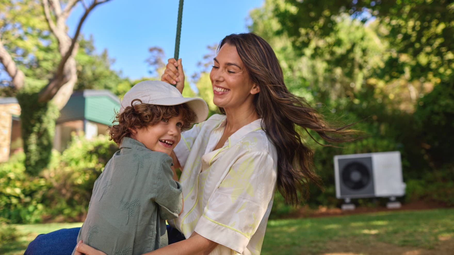 Une mère et son fils dans le jardin devant leur pompe à chaleur