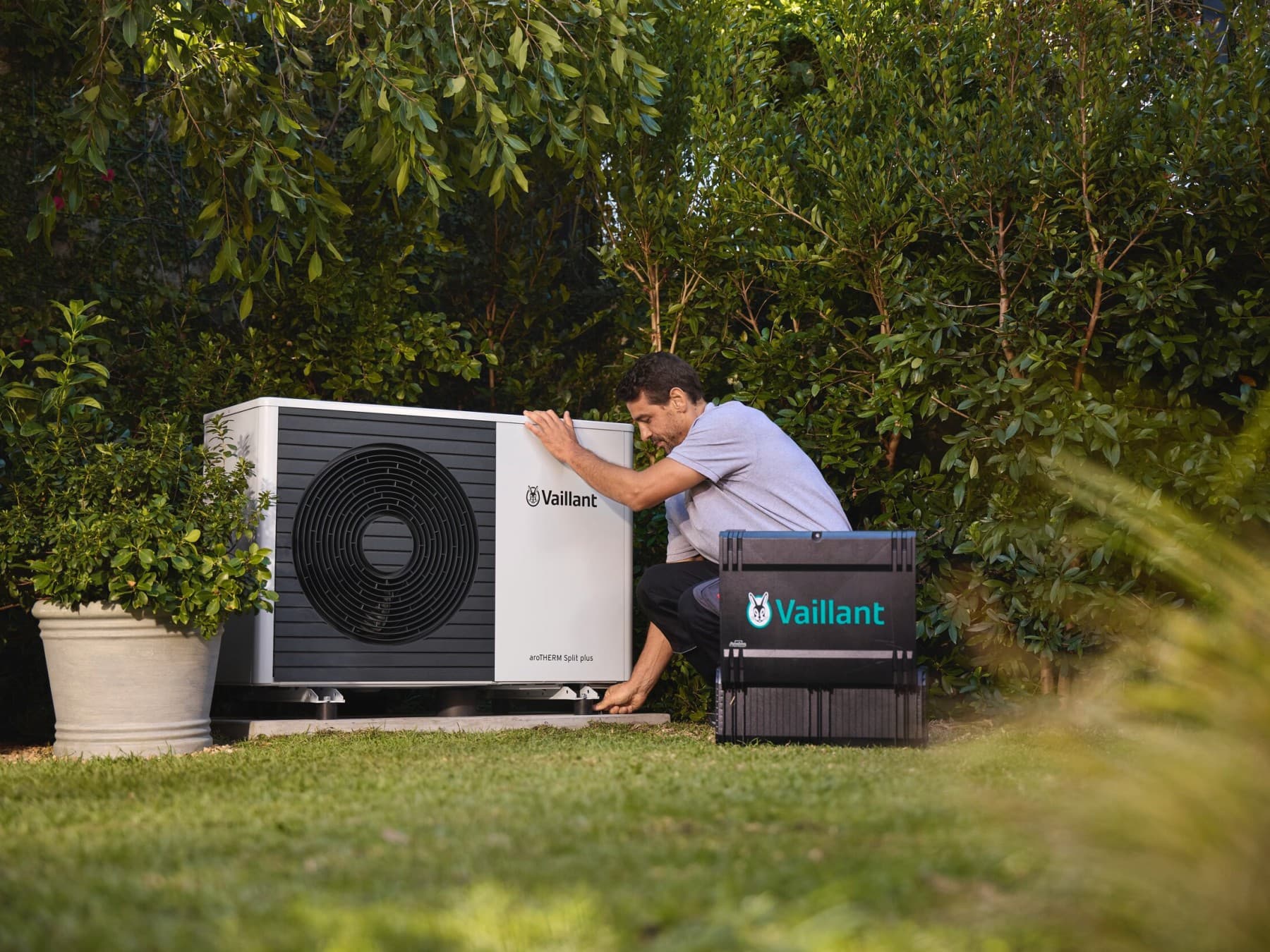 Een installateur die in de tuin aan een warmtepomp werkt