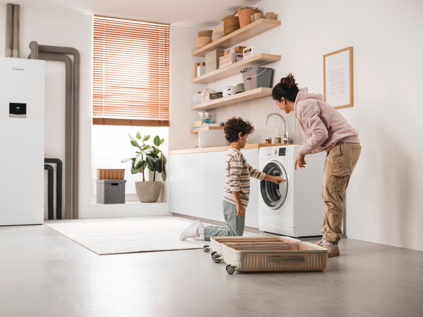 Une mère et son fils vérifient la machine à laver, avec une pompe à chaleur géothermique en arrière-plan