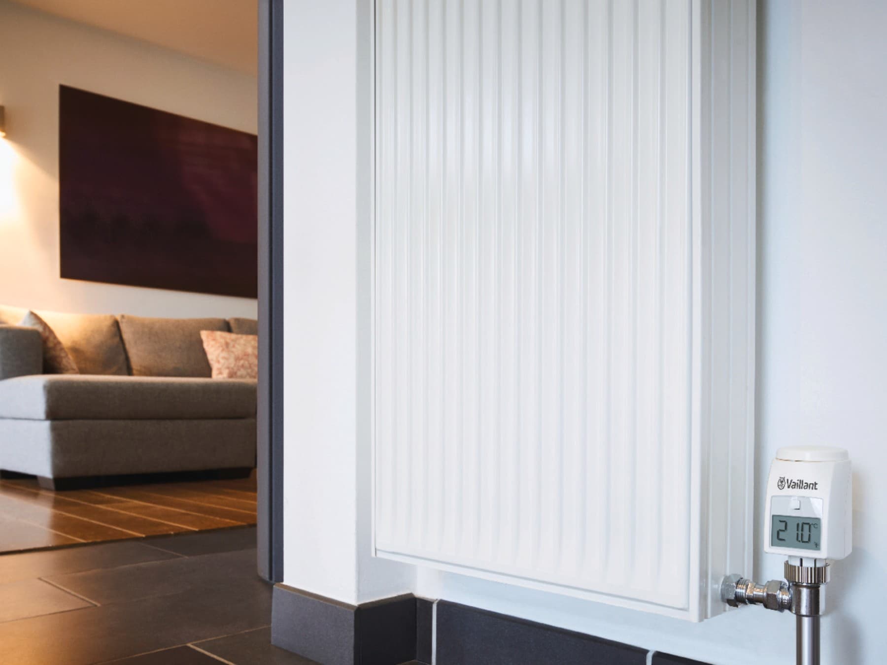 Un radiateur avec, en arrière-plan, un canapé et un éclairage d'ambiance ; l'écran du radiateur affiche 21 °.