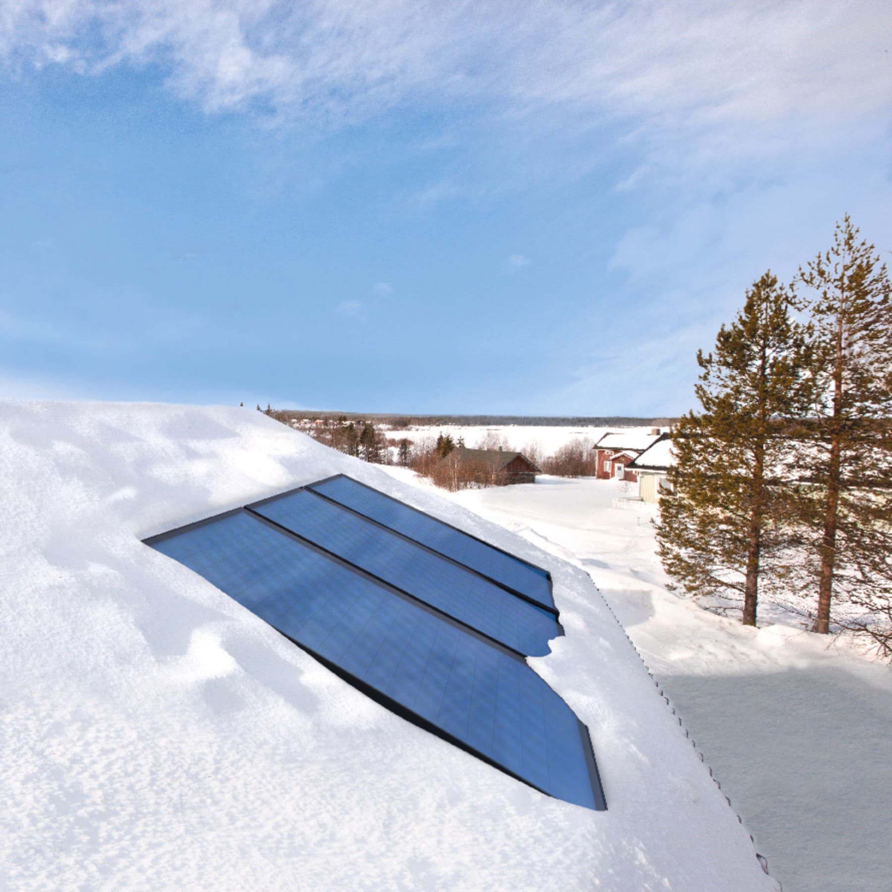Des panneaux solaires intégrés sur un toit enneigé, avec en arrière-plan un ciel bleu et un paysage enneigé