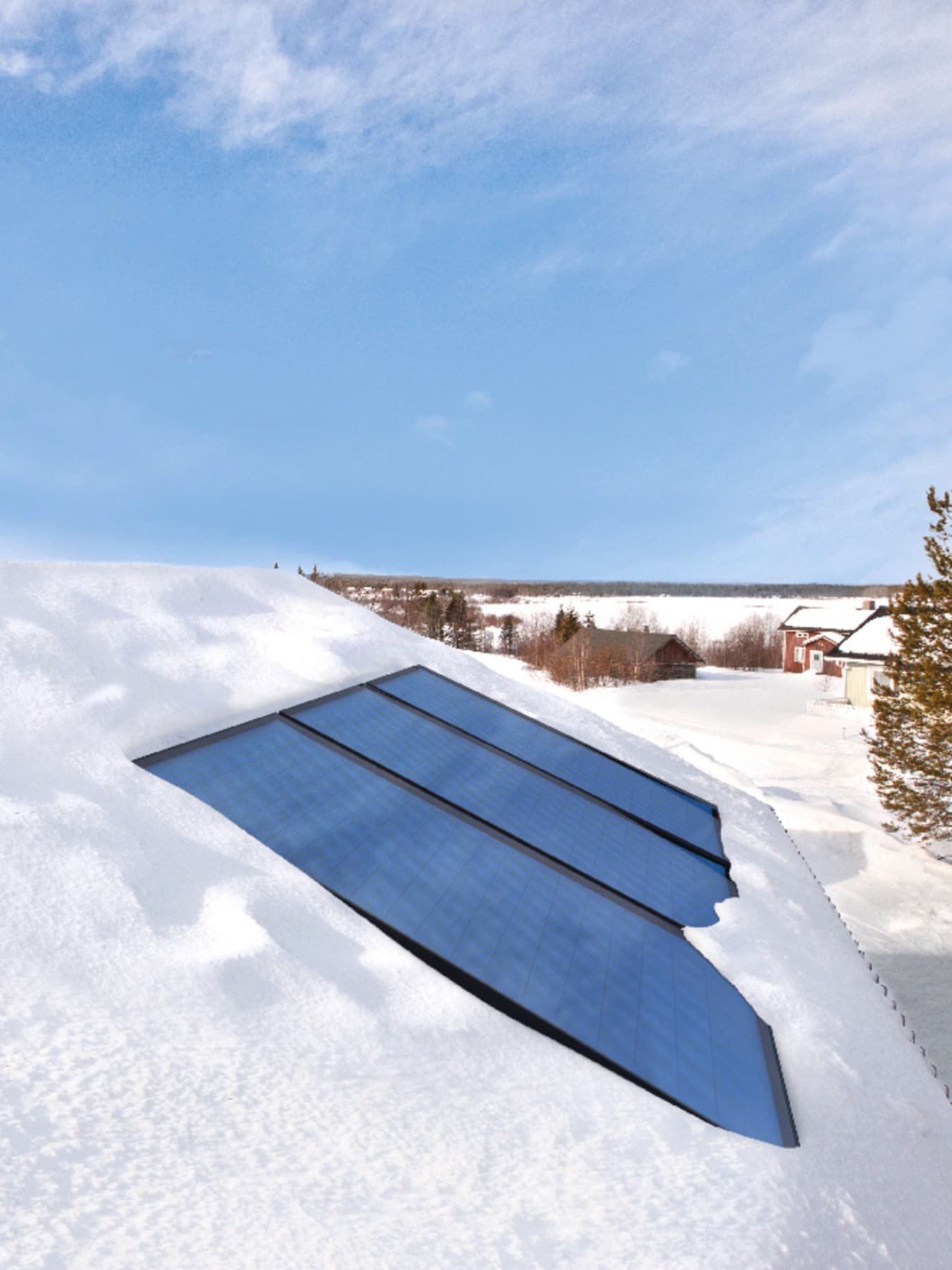 Des panneaux solaires intégrés sur un toit enneigé, avec en arrière-plan un ciel bleu et un paysage enneigé