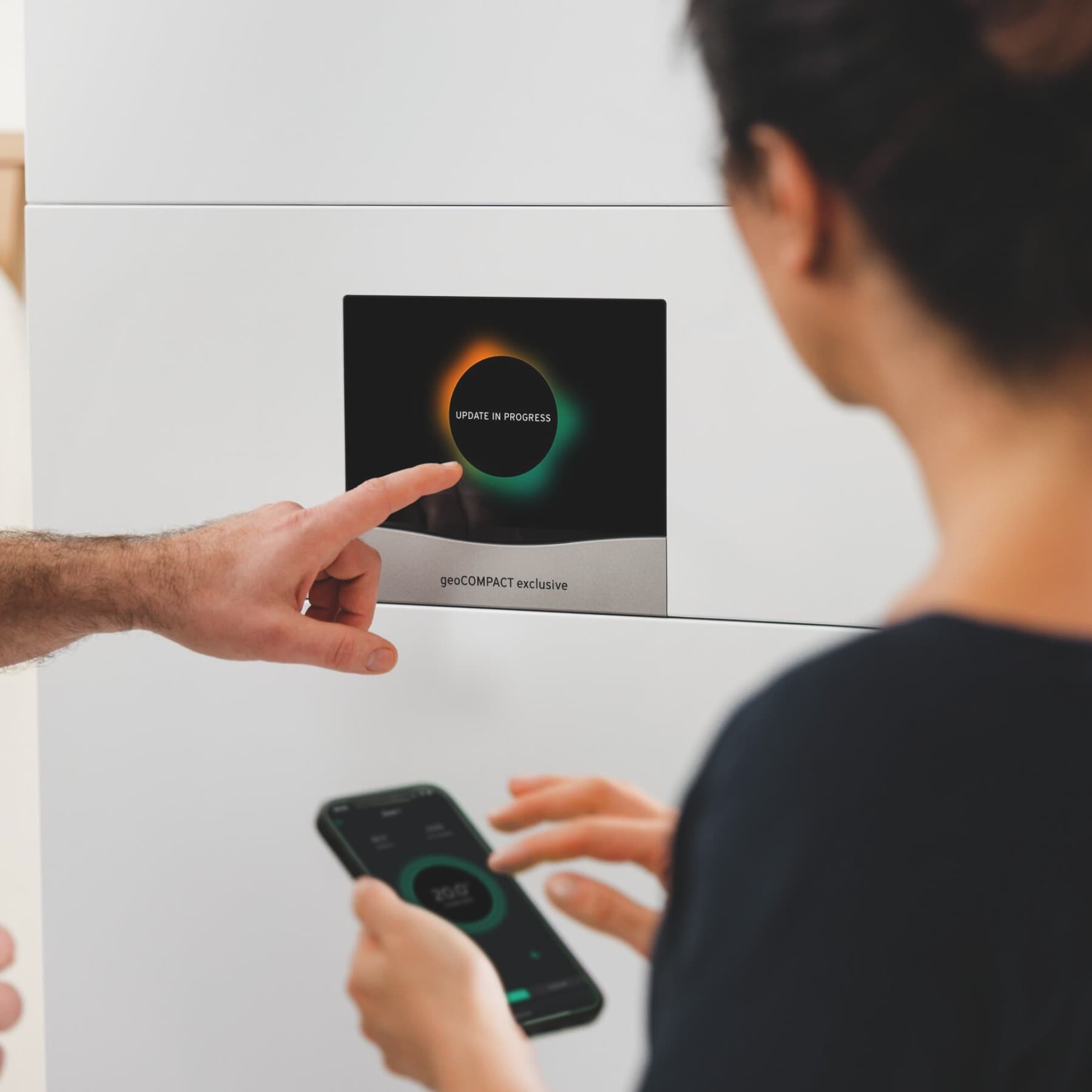Vaillant warmtepomp waarop iemand instellingen wijzigt terwijl vrouw op haar smartphone typt