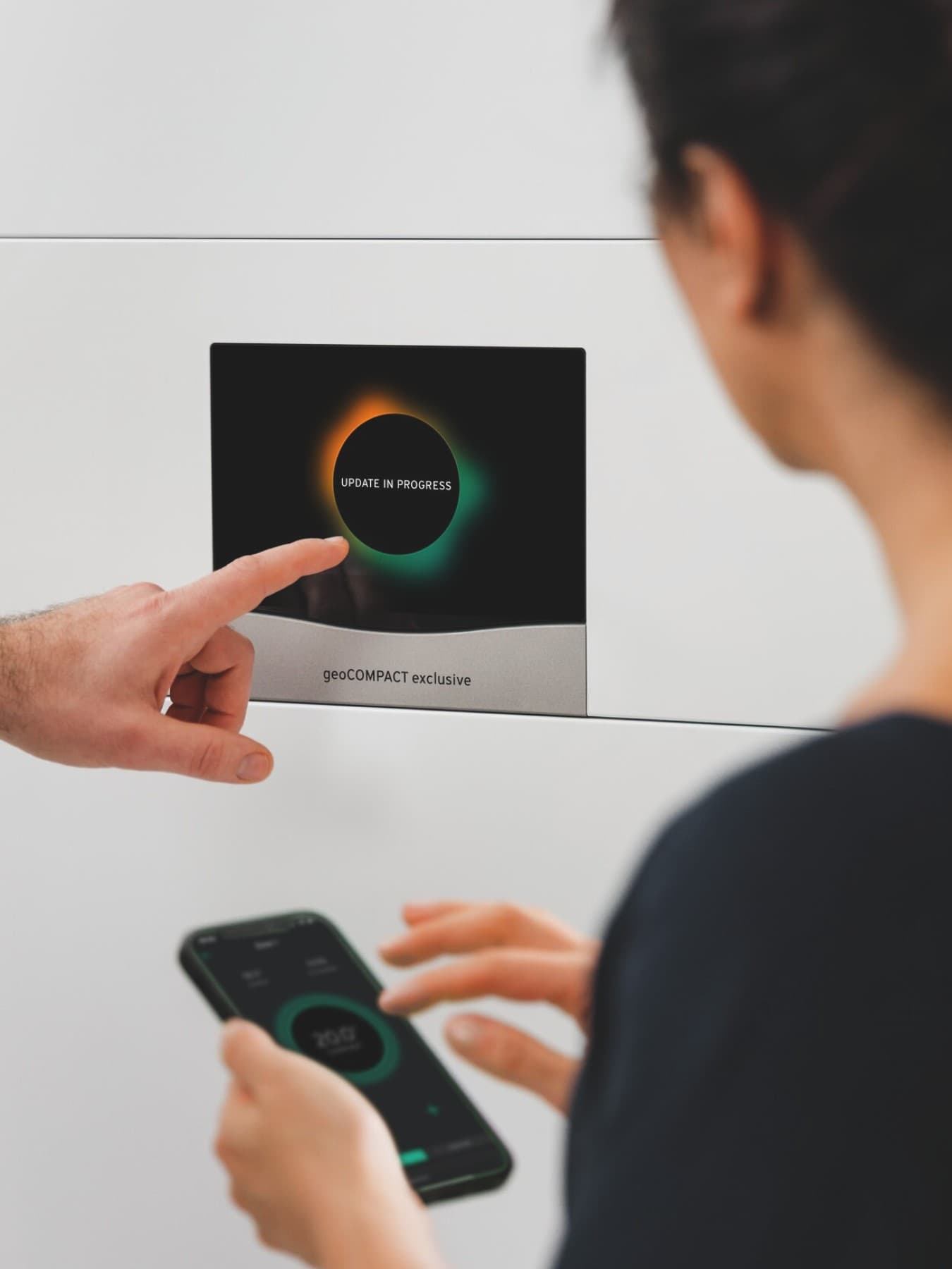 Vaillant warmtepomp waarop iemand instellingen wijzigt terwijl vrouw op haar smartphone typt