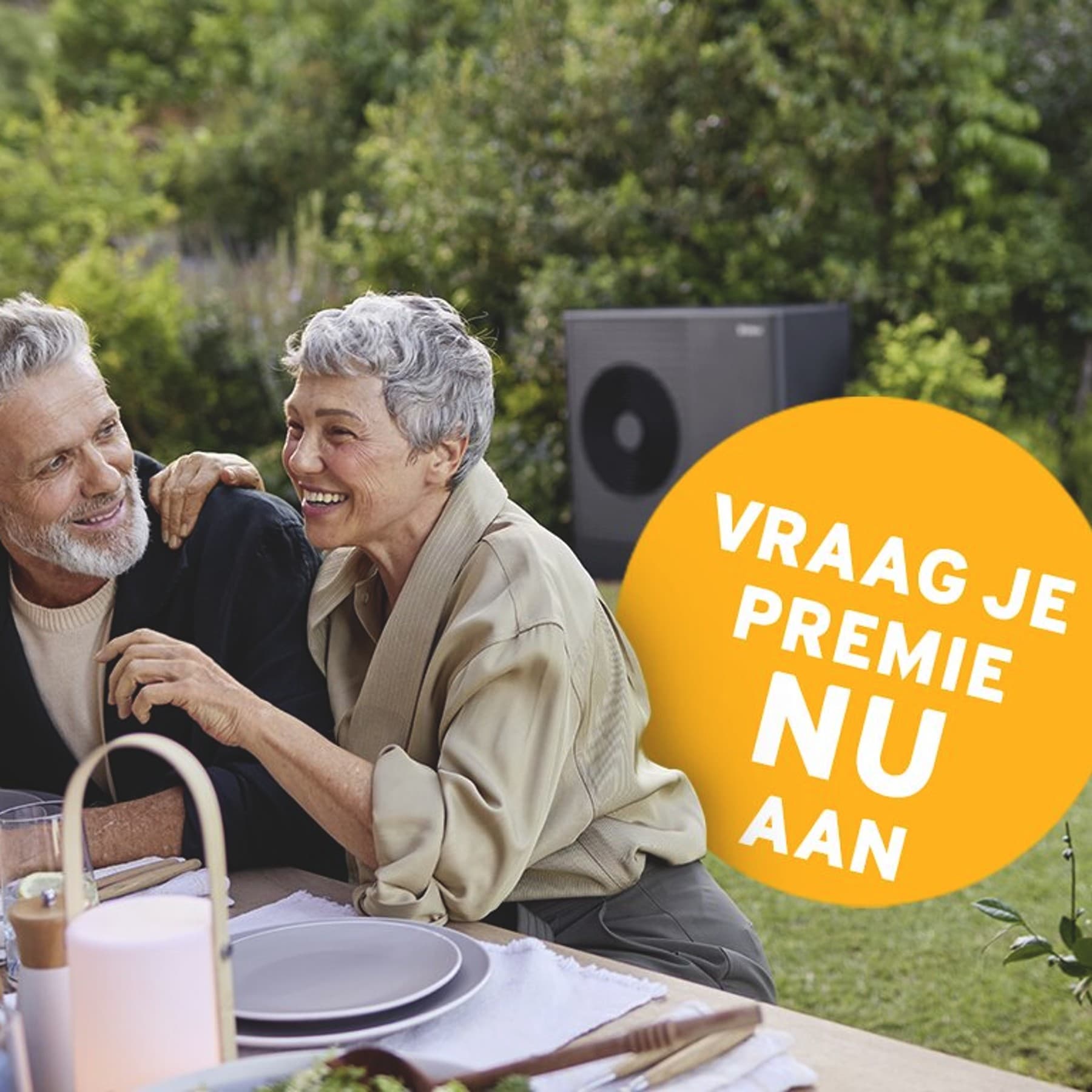 Een stel zit op het terras te eten; op de achtergrond is een warmtepomp te zien.