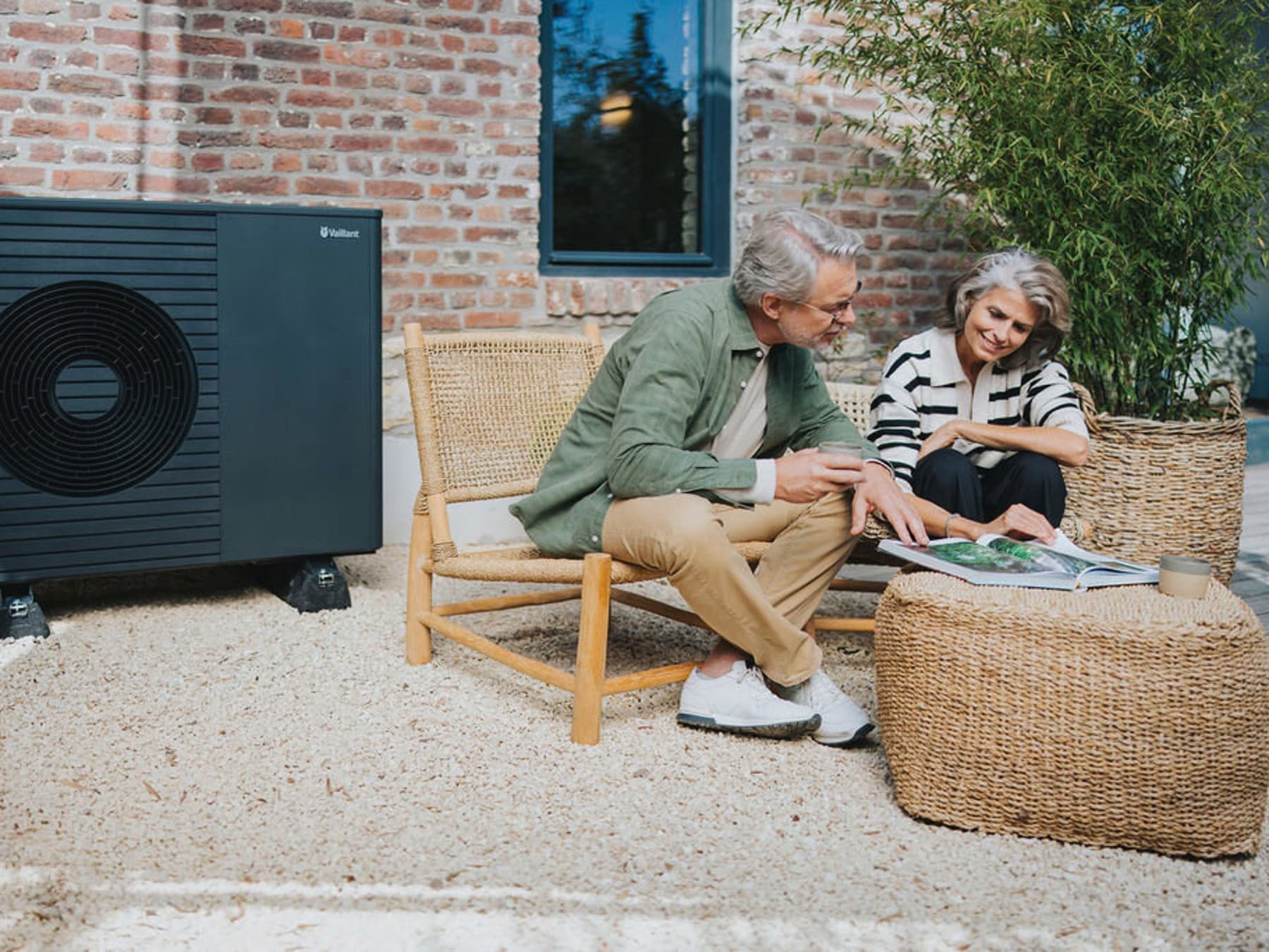 Koppel zit buiten op de achtergrond zie je een warmtepomp
