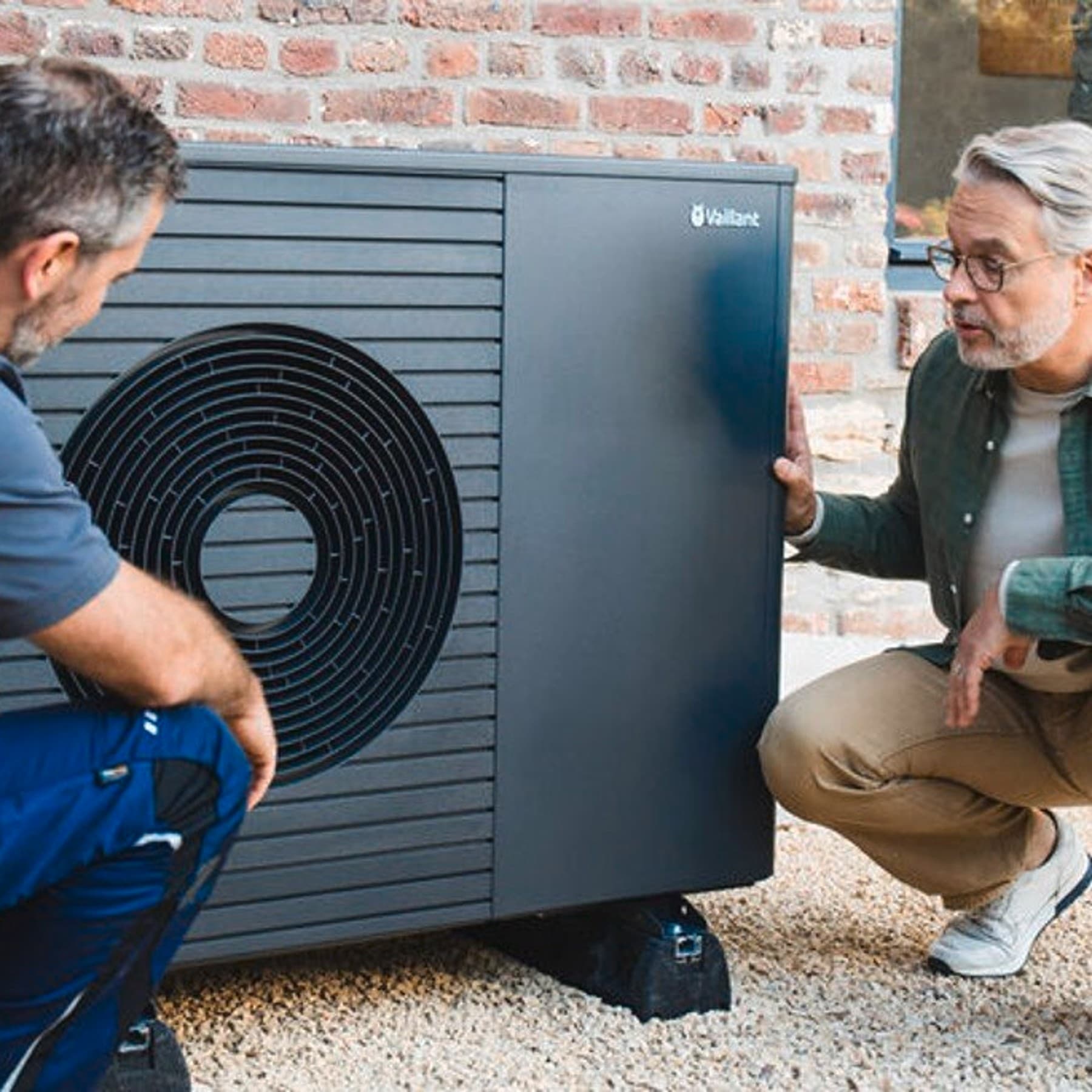 Technicien de service travaillant sur une pompe à chaleur devant un homme