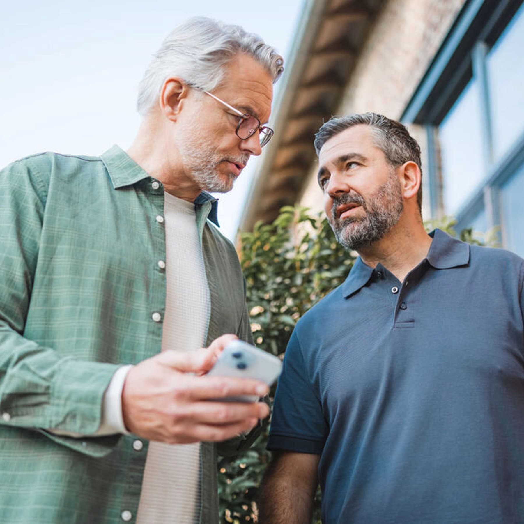 Un homme montre quelque chose à l'installateur sur son smartphone.